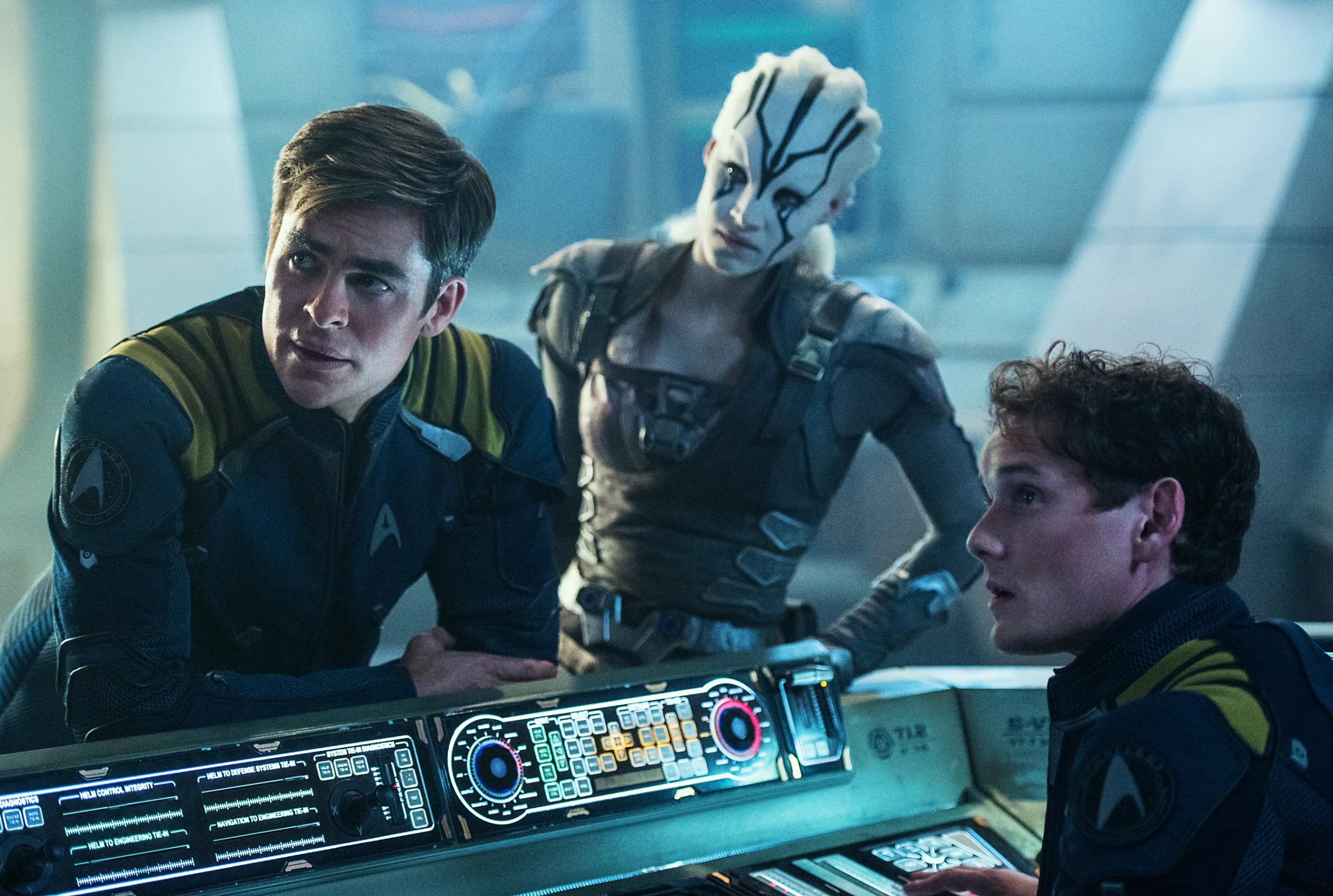 Capitão Kirk (Chris Pine), Jaylah (Sofia Boutella) e Pavel Chekov (Anton Yelchin) debruçados sobre um console em Star Trek Beyond.